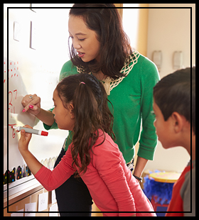 teacher helping students do math on the white board